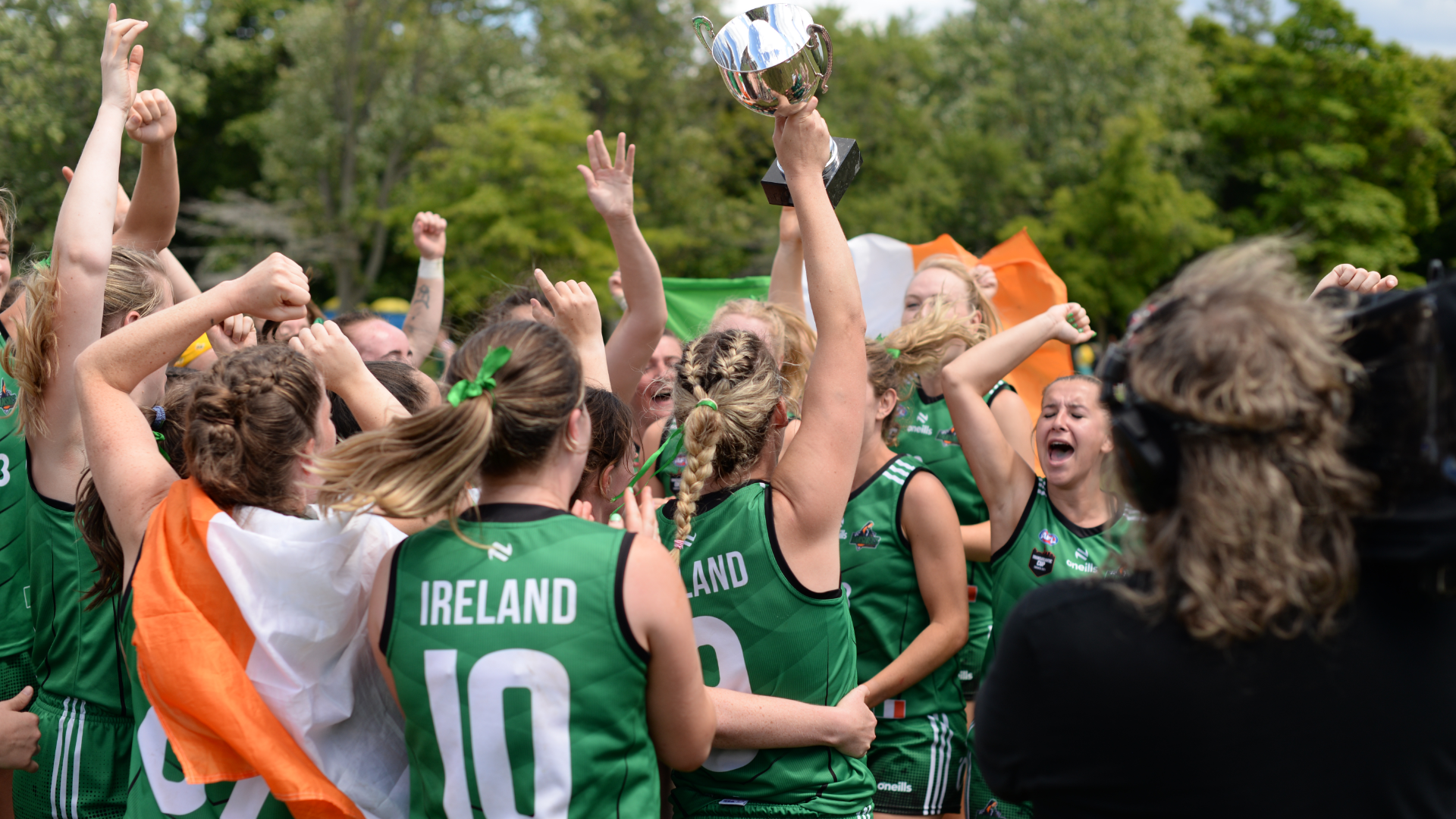 An Irish Women's AFL team celebrates with a trophy