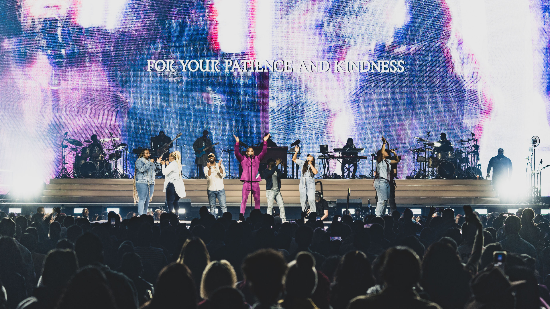 A concert with musicians performing in front of a video wall.